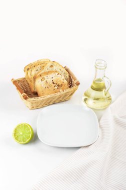 Kızarmış ekmeğin arka planında boş beyaz bir tabak, bir şişe tereyağı ve limon. Metin için boşluk