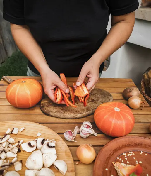 Kadın elleri doğranmış dolmalık biber tutar. Cadılar Bayramı için balkabağı hazırlama süreci. Sebze yemeği tarifi. Fotoğraf serisi