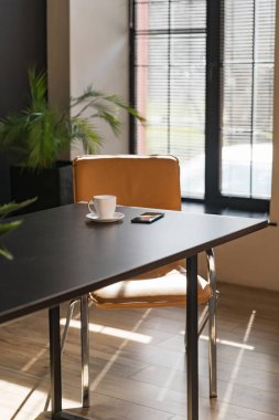 Ofis masasında bir fincan ve bir telefon. Çalışan bir ofisin içinde. İş konsepti. Boşluğu kopyala