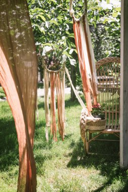 Kurdelelerden yapılmış bahçe dekoru. Bahçedeki ağaçlarda Boho tarzı çelenkler. Bahçede güzel bir dinlenme yeri tasarlamak. Yaşam tarzıyla ilgili bir dizi fotoğraf. Dikey fotoğraf