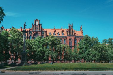 Wroclaw 'daki Neo-Gotik Katolik Papaz Okulu. İsa 'nın heykeli tacın içinde binanın önündeki bir sütunda.