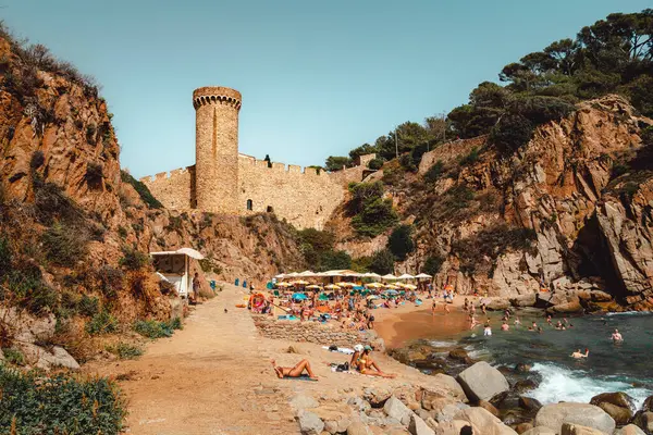Tossa de Mar 'daki Es Codolar plajı. Şehrin bir parçası ve kule arka planda.