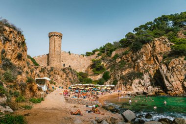 Tossa de Mar 'daki Es Codolar plajı. Şehrin bir parçası ve kule arka planda.