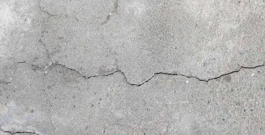 Çatlak duvar dokusu. Arka plan olarak çimento yüzeyi ile kaplı çatlamış beton duvar. Çizik ve çatlaklarla dolu bir duvar parçası.