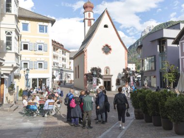 Ortisei, İtalya - 13 Haziran 2024: Ortisei 'deki Aziz Antonius Kilisesi önündeki turistlere bakış
