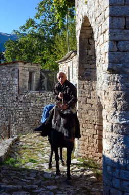 Kalarrytes, Yunanistan - 25 Ekim 2019: Bir adam geleneksel Epirus köyünde katırına biniyor