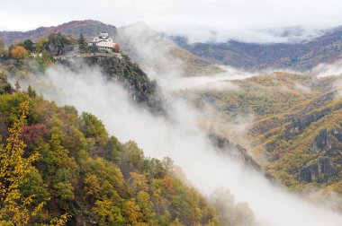View of the Metamorphosis Sotiros monastery in a landscape with autumnal colorful foliage and clouds at Mount Rodopi, near the village of Paranesti in northern Greece clipart