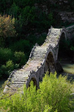 View of the traditional stone Kalogeriko or Plakida bridge near the village of Kipoi in Zagori of Epirus, Greec clipart