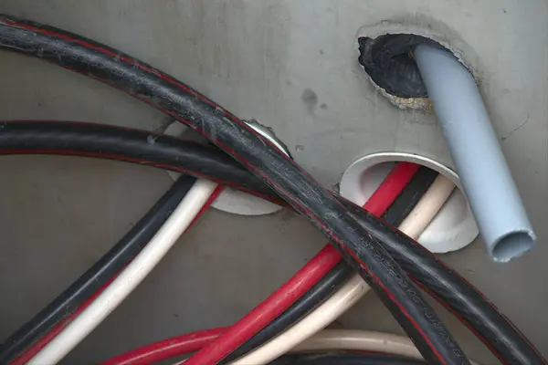 Beton duvardan çıkan elektrik kabloları