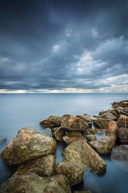 Flevoland 'daki Urk köyü yakınlarındaki IJsselmeer Hollanda' da yaklaşan yağmur ve fırtına bulutlarıyla kayaların kıyılarından göl manzarası