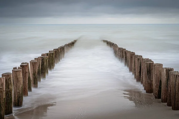荷兰多姆堡海滩上的防浪堤 长期曝光的照片 动态的海浪在木板柱子上冲破了海岸 — 图库照片