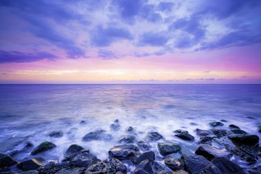 Deniz kıyısında gün batımı. Batı Kapelle, Zeeland, Hollanda 'da, pastel gökyüzünün altındaki kaya oluşumlarına çarpan dalgaların çarpıcı görüntüsü
