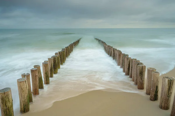 オランダのDomburgのビーチで波のブレーカ 木製の柱の上の海岸で破壊するダイナミックな波と長い露出写真 — ストック写真