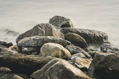 Deniz kıyısındaki kaldırım taşları ve kayalar uzun pozlu çekimler yoluyla pürüzsüz suyla