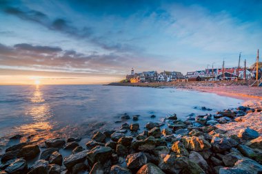 Alacakaranlıkta deniz feneriyle birlikte sahil. Hollanda 'da parlak bir yaz günü tarihi Urk köyünde. Alacakaranlıkta IJsselmeer Gölü' nün yanında..