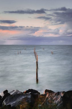 IJsselmeer 'de atmosferik günbatımında sonsuz ufuk çizgisi olan bir bisikletle uzun pozlama fotoğrafı, IJsselmeer, Hollanda