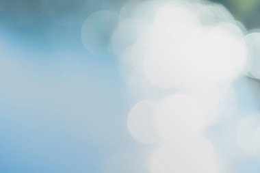 Görüntü büyük, parlak, dairesel ışık şekillerinin beyaz ve açık mavi-gri gradyan arkaplanlarına karşı bulanık olduğunu gösteriyor.