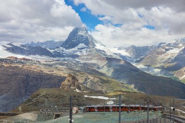 İsviçre Alplerindeki Matterhorn dağının arka planındaki kırmızı tren.