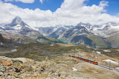 İsviçre Alplerindeki Matterhorn dağının arka planındaki kırmızı tren.