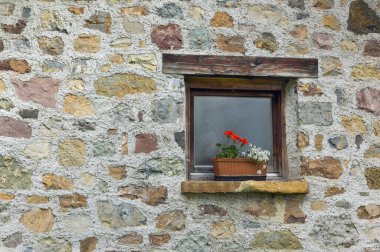 Taş duvarın arka planında çiçekler olan güzel bir pencere.