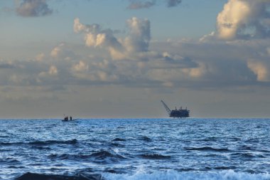 Tekne İsrail 'de gün batımında gökyüzüne karşı gaz platformuna gidiyor.