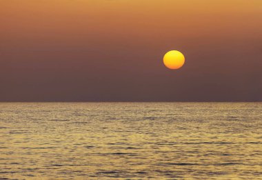 Güzel sarı kırmızı güneş çemberi gün batımında denizin üzerinde.