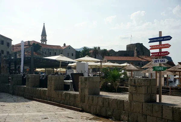 ブドヴァ モンテネグロ 2023年6月25日 旧市街の城壁要塞を背景にブドヴァビーチのわらぶき屋根の傘の下のサンラウンジャー — ストック写真