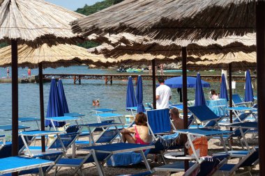       Budva, Karadağ - 25 Haziran 2023: Deniz kenarındaki saman plaj şemsiyeleri, Straw Beach şemsiyesi, Eski Budva plajı, Karadağ                         