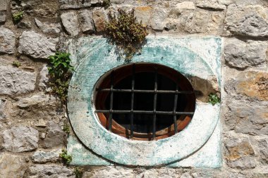    Budva Eski Kasabası, Eski Budva, Karadağ sokaklarında parmaklıklı oval taş pencere                            