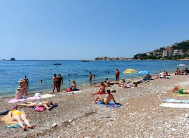 Budva, Karadağ - 19 Haziran 2023: Budva sahilinde yaz boyunca güneşlenen ve dinlenen insanlar.