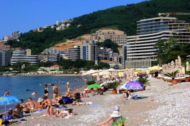 Budva, Karadağ - 19 Haziran 2023: Budva sahilinde yaz boyunca güneşlenen ve dinlenen insanlar.