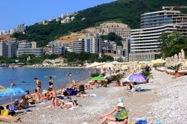 Budva, Karadağ - 19 Haziran 2023: Budva sahilinde yaz boyunca güneşlenen ve dinlenen insanlar.