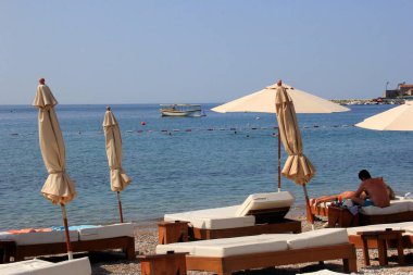 Budva, Karadağ - 19 Haziran 2023: Budva sahilinde yaz boyunca güneşlenen ve dinlenen insanlar.