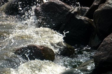 Deniz suyu kıyıdaki siyah kayalara sıçrar.                               