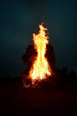 Letonya 'da gece yarısı büyük bir şenlik ateşi. Koyu arkaplan ile yanan şenlik ateşi