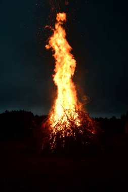 Letonya 'da gece yarısı büyük bir şenlik ateşi. Koyu arkaplan ile yanan şenlik ateşi