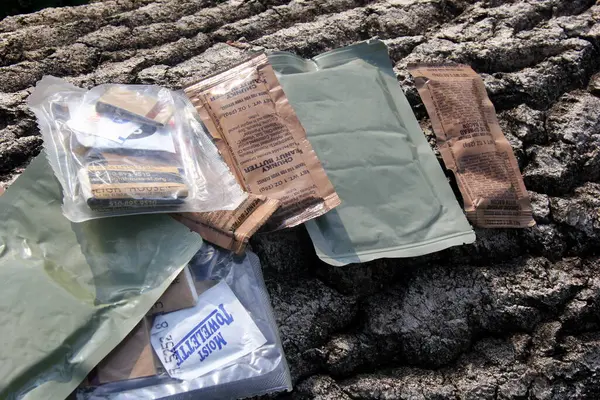 stock image Riga, Latvia, - 23 June 2024 : Several Individual Food Rations for USA soldiers. Pack of Meal, Ready to Eat (MRE) food, USA army military food kit on tree bark background