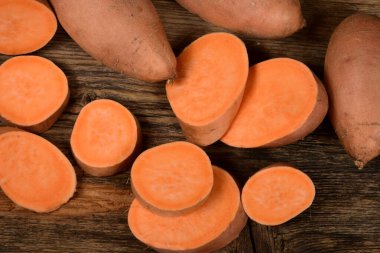 Dilimlenmiş ve çiğ patates. Koyu arkaplan. Tatlı batata, sebze bahçesi.