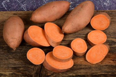 Dilimlenmiş ve çiğ patates. Koyu arkaplan. Tatlı batata, sebze bahçesi.