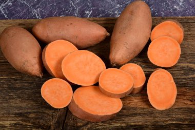 Dilimlenmiş ve çiğ patates. Koyu arkaplan. Tatlı batata, sebze bahçesi.