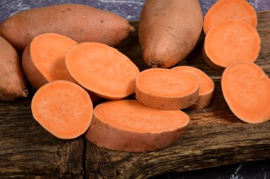 Dilimlenmiş ve çiğ patates. Koyu arkaplan. Tatlı batata, sebze bahçesi.