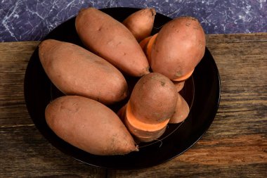 Dilimlenmiş ve çiğ patates. Koyu arkaplan. Tatlı batata, sebze bahçesi.