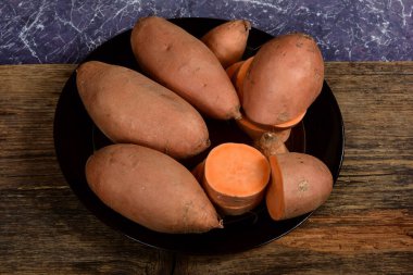 Dilimlenmiş ve çiğ patates. Koyu arkaplan. Tatlı batata, sebze bahçesi.