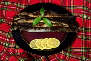 Fried lampreys on a plate and in a dish. Latvian lamprey recipes clipart