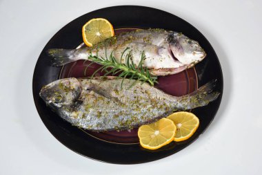 Limon ve baharatla süslenmiş iki pişmemiş taze dorada. Dorado tarifleri, beyaz arkaplan