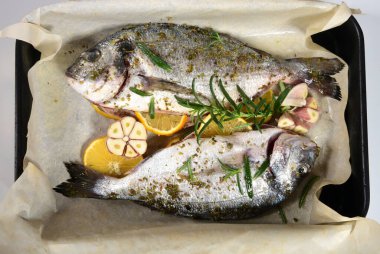 Limon ve baharatla süslenmiş iki pişmemiş taze dorada. Dorado tarifleri, beyaz arkaplan