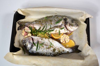 Limon ve baharatla süslenmiş iki pişmemiş taze dorada. Dorado tarifleri, beyaz arkaplan