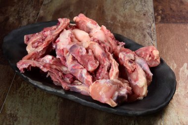 Siyah kil tabakta etli tavuk kemikleri, kahverengi taş arka plan. Tavuk çorbası seçimi