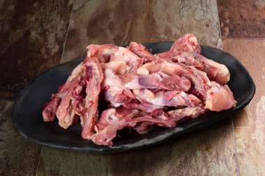 Siyah kil tabakta etli tavuk kemikleri, kahverengi taş arka plan. Tavuk çorbası seçimi