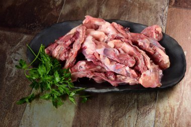 Siyah kil tabakta etli tavuk kemikleri, kahverengi taş arka plan. Tavuk çorbası seçimi